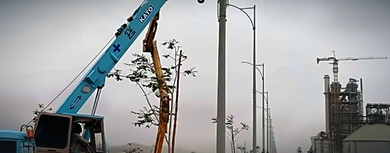 Street lighting poles being installed along the plant road at DG Cement Hub plant